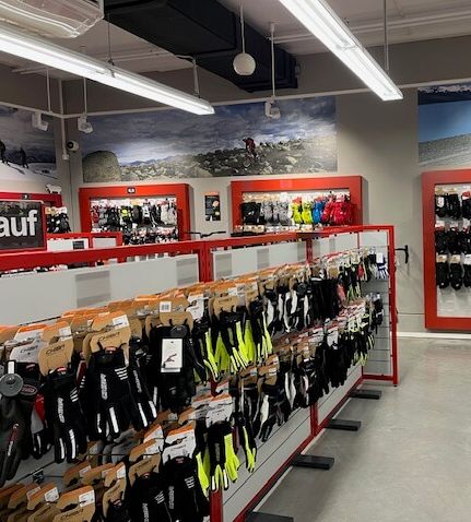 Moderne Sportgeschäftsabteilung mit Handschuhen, gut sortiert und hell beleuchtet.
