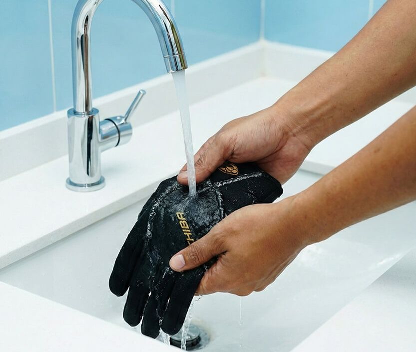 Hände waschen Handschuh unter fließendem Wasser in Spüle.